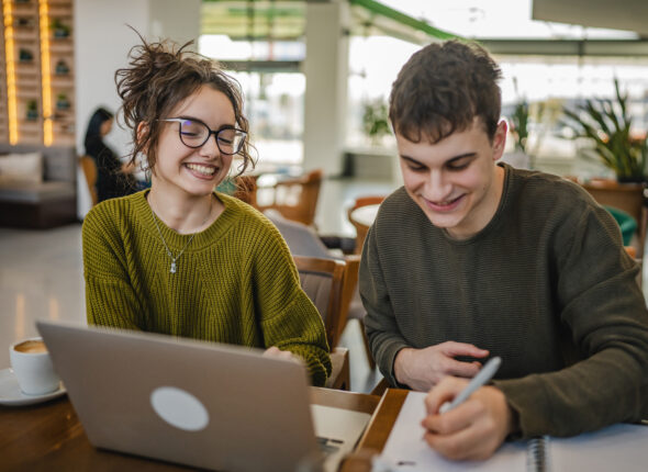 young couple work together and learn on laptop at cafe
